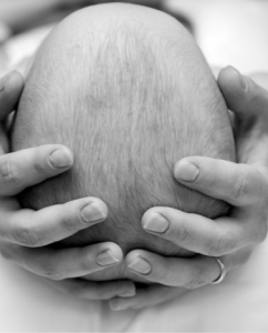 A physician's hands gently cradling an infant's head